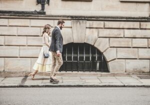 man and woman walking beside a road during daytime